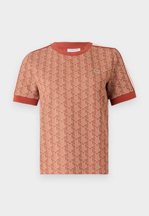 Rövid ujjú póló terrakotta színben, texturált geometriai mintával, bordázott kerek nyakkal és kontrasztos piros részletekkel az ujjakon.