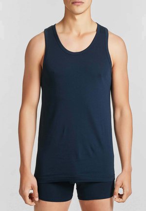 Canottiera blu navy senza maniche in tessuto morbido con scollo rotondo e dettagli di cuciture minime, abbinata a pantaloncini scuri.