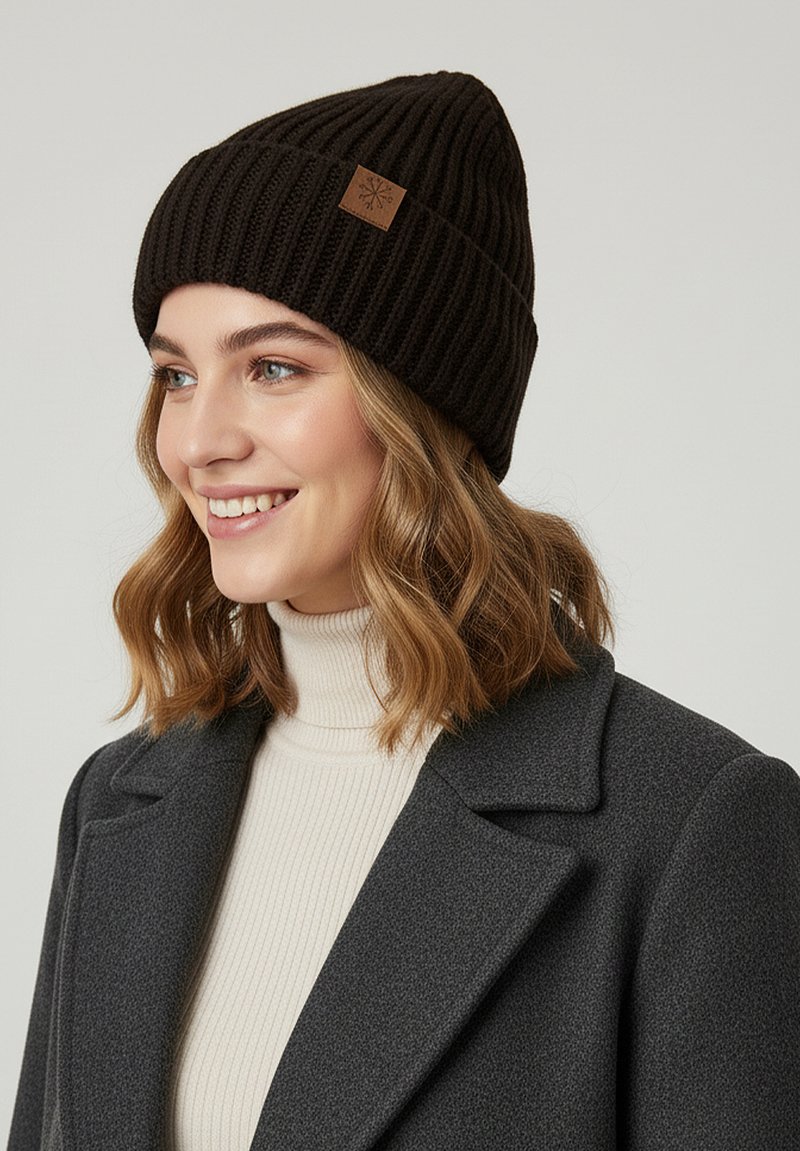 Black ribbed knit beanie with a soft texture and a fold-over design, featuring a small brown leather patch detail.