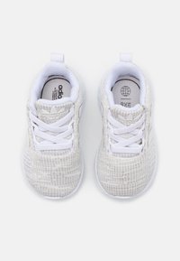 Bílé sportovní boty s texturovaným pleteným svrškem, zavazováním na tkaničky a polstrovanou podrážkou. Na jazyku a boku je umístěno logo značky.