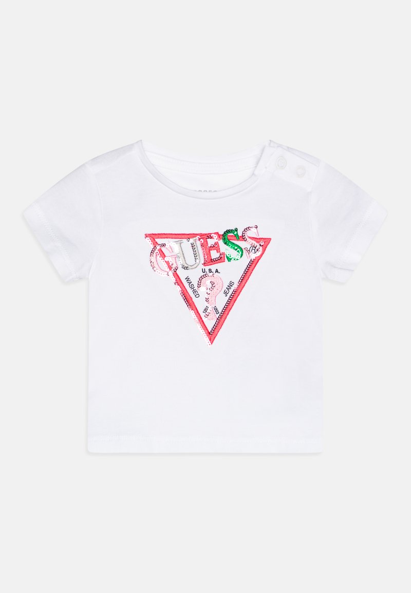 T-shirt branca de manga curta com um gráfico triangular em vermelho e verde, adornado com lantejoulas, que representa a palavra "GUESS" e um detalhe do logótipo.
