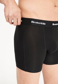 Černé boxerky vyrobené z hladké tkaniny, s přiléhavým střihem a elastickým pasem se znakem "Resteröds" v bílé barvě.