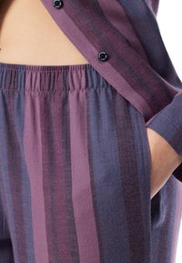 Fialová a modrá pruhovaná látka s herringbone vzorem. Obsahuje elastický pas a knoflíkový detail uvršku. Zahrnuje kapsy.
