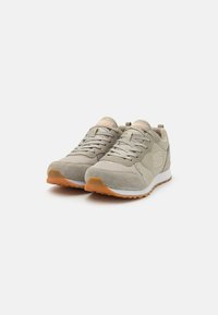 Light grey athletic shoes with mesh and suede materials, featuring beige laces, orange accents, and rubber soles with traction patterns.