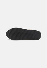 Suola in gomma nera con texture rigata; leggera, progettata per una buona aderenza; parte di una sneaker con tomaia in mesh.