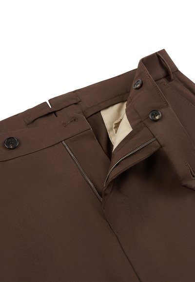Pantalon marron avec fermeture éclair avant partiellement ouverte, deux boutons noirs sur la ceinture, et doublure intérieure beige visible.