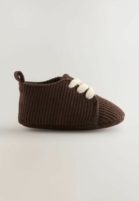 Brune kordfløjslippers med rund tå, hvide snørebånd og en blød, fyldig sål. Har en lille løkke bagpå for nem påtagning.