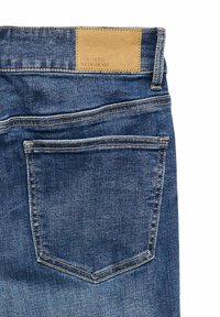 Tumesinised teksapüksid, millel on sile tekstuur. Omavad tan-värvi nahast plaastrit, millele on pressitud "VERO MODA WE DO DENIM" ning kontrastse õmblusega.