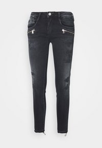 Vaqueros de denim negro con un ajuste slim, con bolsillos con cremallera en el frente, detalles desgastados y cremalleras en los tobillos. Textura suave, diseño casual.