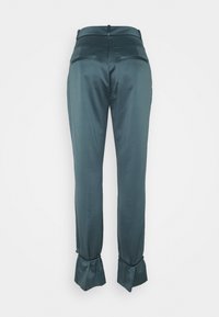 Pantaloni su misura in satin color verde scuro, con vita aderente, tasche posteriori piatte e polsini svasati con dettagli in bottone. Texture liscia.