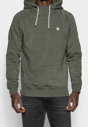 Grön hoodies med strukturerad yta, snedställda sömmar och vita dragsnören. Har en liten logotyp på bröstet.
