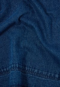 Sötétkék farmeranyag sima textúrával, finom bordás mintázattal és látható varrással a varratok mentén.