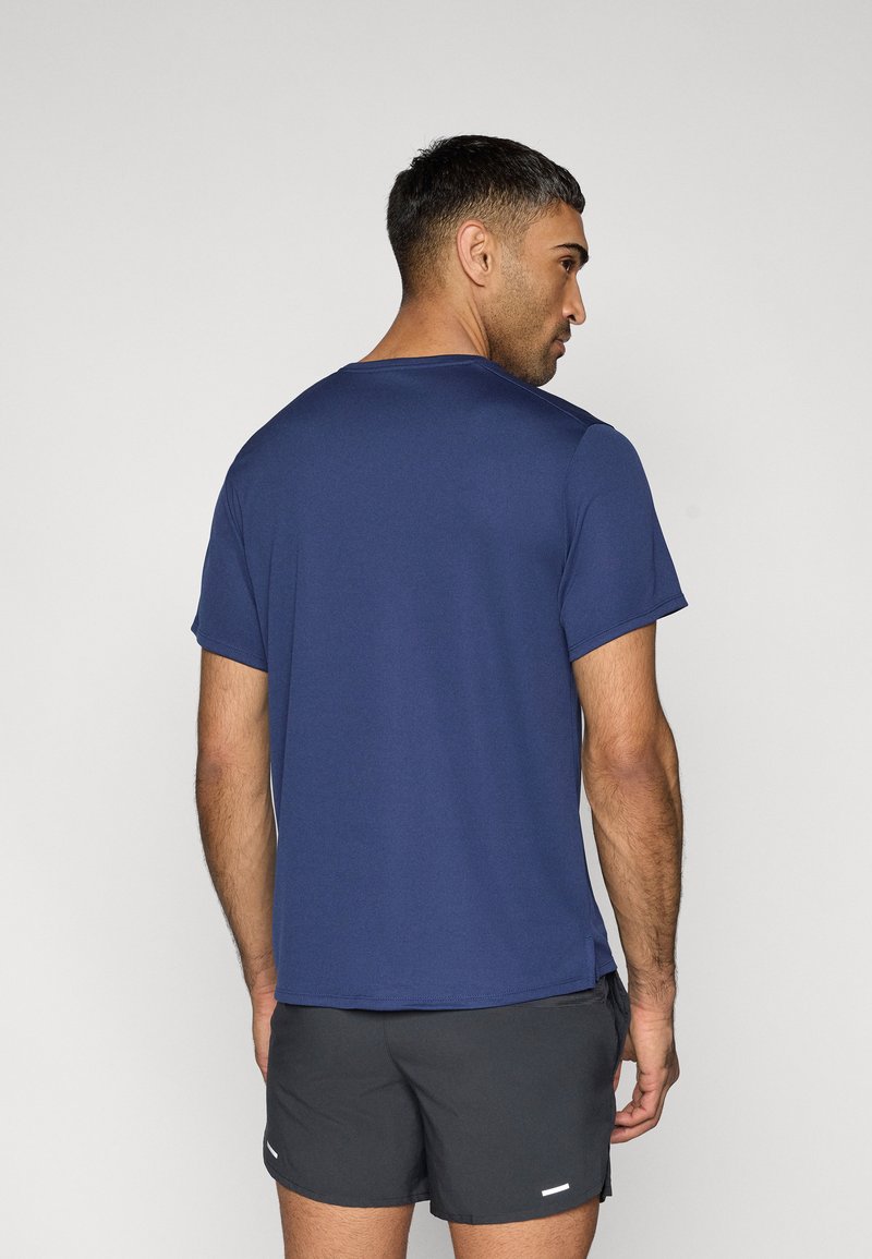 Marineblaue Kurzarm-T-Shirt aus leichtem Stoff, Rundhalsausschnitt, mit Seitenschlitzen, getragen mit dunkelgrauen Shorts, zeigt einen lässig-athletischen Stil.