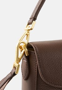 Brun lædertaske med struktur og guldhardware. Indeholder en guldkrog og en justerbar rem med tekstureret finish.