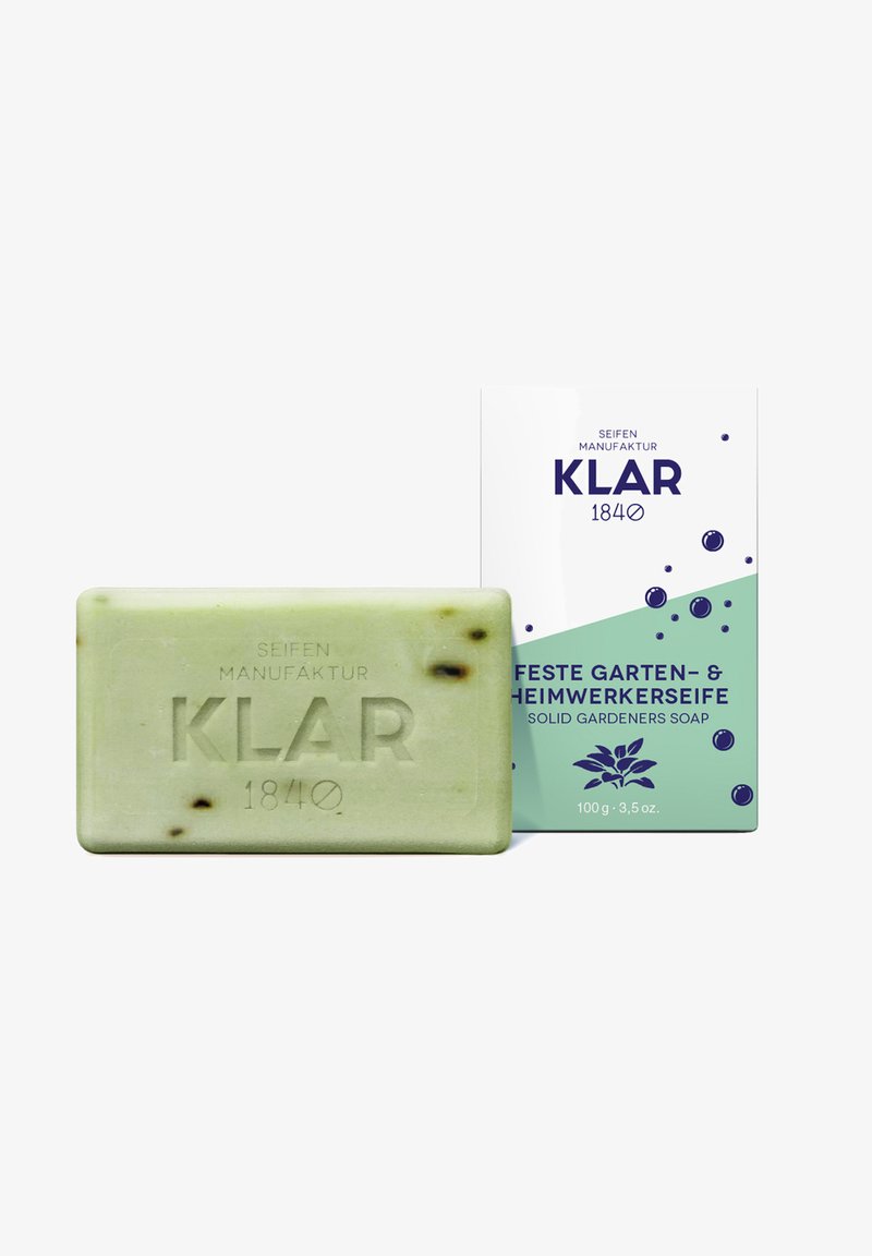 Green rectangular soap bar with "KLAR 1840" embossed, shown next to white and green packaging labeled solid gardeners soap, 100g.