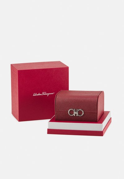 Punane nahast ehtekarp hõbedase riistvara klambriga, millel on tekstureeritud pind ja ümarad servad, kaasas sobiv punane vitriinkarp.