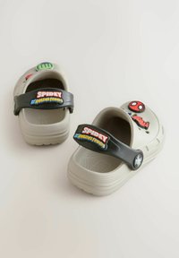 Hellgraue Clogs mit einer strukturierten Oberfläche, ausgestattet mit einem schwarzen Riemen, der mit bunten "Spidey"- und Charakterakzenten verziert ist.
