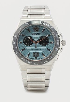 Sølv Versace kronografur med blå mønstret urskive, to sorte underskiver, datovisning og armbånd i rustfrit stål.