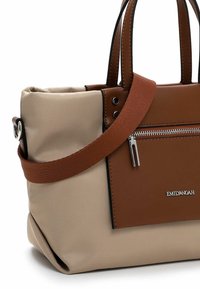 Beige nylon kantokassi ruskeilla nahkakoristeilla, jossa on kaksi yläkahvaa, irrotettava olkahihna ja etupuolella vetoketjullinen tasku.