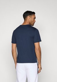 Sötétkék, rövid ujjú póló sima anyagból, kerek nyakkivágással és normál szabással, letisztult, minimalista dizájnnal.