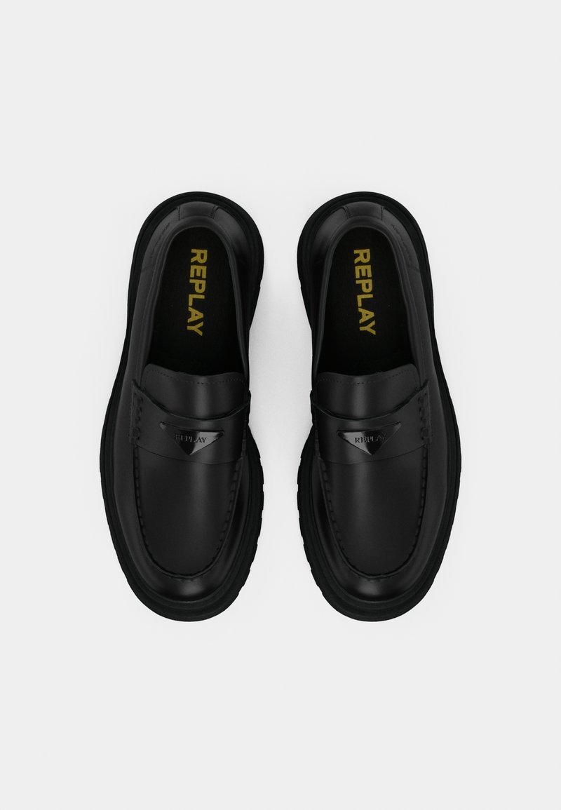 Scarpe slip-on nere con una tomaia in pelle liscia, suola strutturata e un accento decorativo in argento. Branding interno giallo.