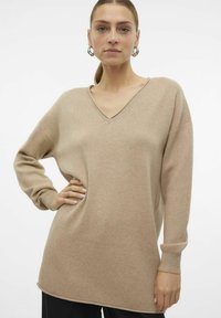 Beige V-Ausschnitt-Pullover aus weichem Material mit langen Ärmeln, gerippten Bündchen und lässiger Passform, mit einer glatten Textur und dezenten Nähten.