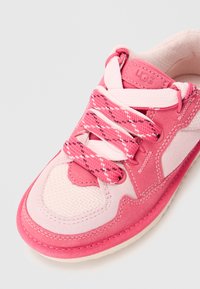 Scarpa sportiva rosa con tomaia testurizzata, materiali in suede e rete, lacci decorativi e tonalità a contrasto nella suola.