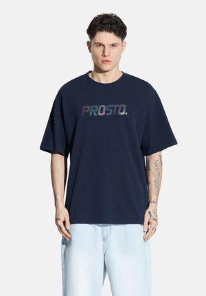 Granatowa, oversize'owa koszulka wykonana z bawełny, z kolorowym logo „PROSTO.” nadrukowanym na piersi. Krótkie rękawy i okrągły dekolt.