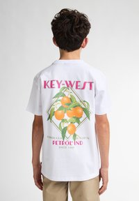 Witte t-shirt met korte mouwen, voorzien van een kleurrijke oranje graphic en tekst met "KEY-WEST" en "PETROL IND" op de achterkant.