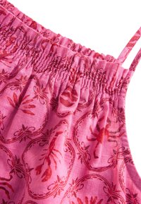 Tessuto rosa con superficie testurizzata che presenta un motivo ripetuto di aragoste in rosso e rosa scuro, arricciato nella parte superiore con sottili spalline.