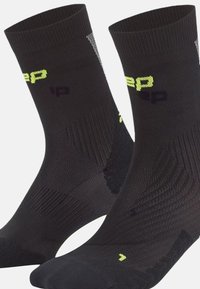 Socks sportivi neri con texture a costine, tallone e punta rinforzati. Presentano un marchio giallo brillante e nero. Design alla caviglia.