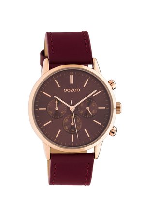 Analoge Armbanduhr mit einem runden, dunkelbraunen Zifferblatt, roségoldenen Zeigern und drei Hilfszifferblättern. Ausgestattet mit einem bordeauxfarbenen Lederarmband mit Naht.