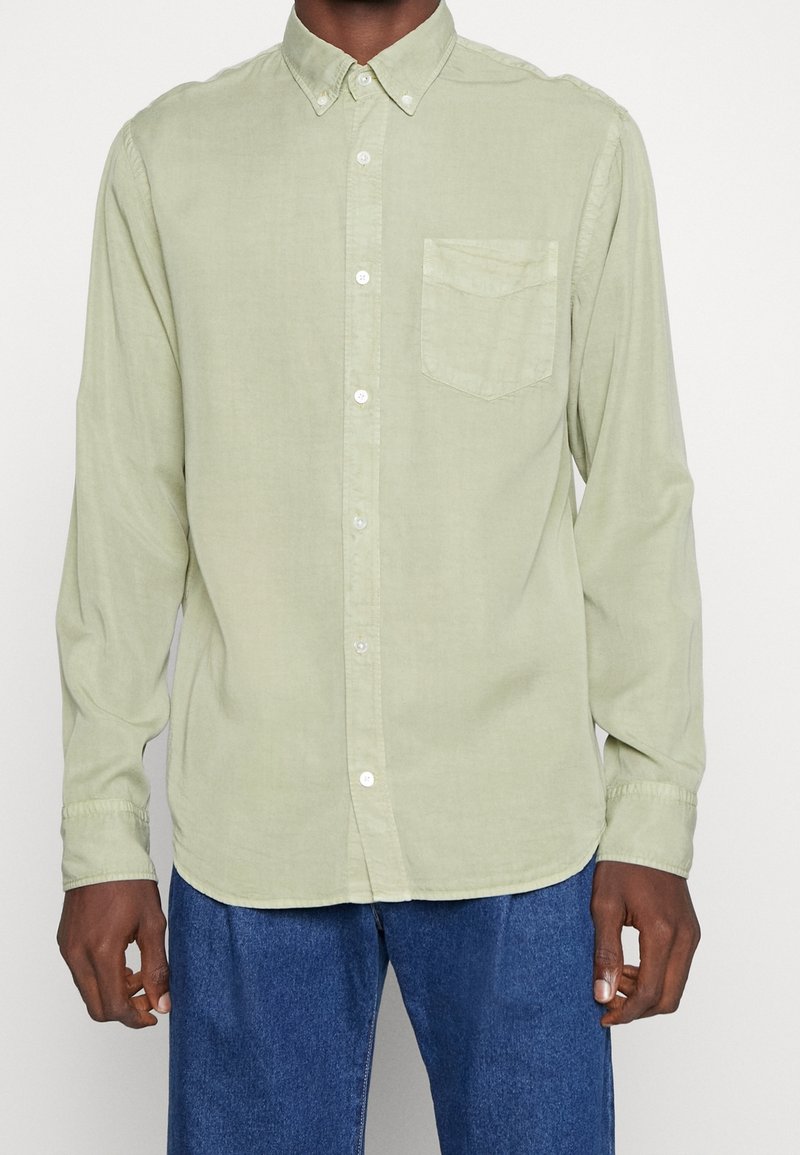 Camicia a maniche lunghe verde chiaro con colletto botton-down, taschino sul petto singolo e bottoni bianchi. Tessuto morbido e strutturato.