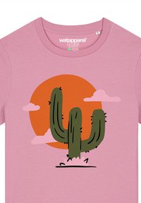 Roze katoenen t-shirt met een afbeelding van een groene cactus tegen een oranje zon en roze wolken, met zwarte contouren en details.
