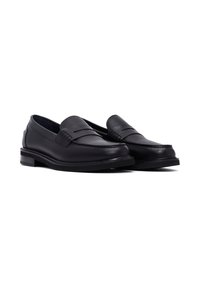 Mocasines de cuero negro con un acabado suave, que presentan un diseño de hebilla para moneda y un tacón bajo apilado. Detalles texturizados en la parte superior.