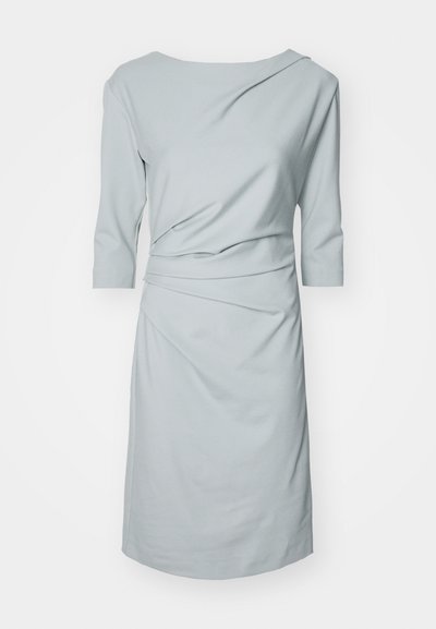 Šviesiai mėlyna suknelė iš minkštos medžiagos, turinti valtiniu iškirpimu, trijų ketvirtadalių rankovėmis ir susiraukšlėjimo detalių, suteikiančių drapiruotą efektą.