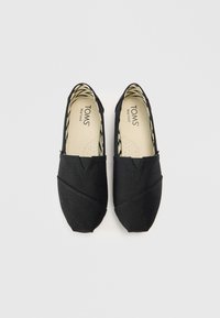 Czarne wsuwane buty wykonane z płótna o fakturowanej powierzchni, z trójkątnym wzorem wycięcia i wzorzystą podszewką wewnętrzną.