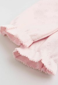 Vaaleanpunainen neulottu kangas, jossa aaltoileva pitsireunus ja pienet timantinmuotoiset rei'ityskuviot, todennäköisesti vauvan tai lapsen vaatteen kalvosin.