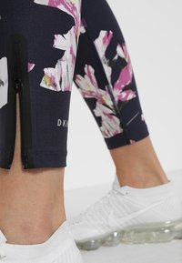Legíny s květinovým vzorem v námořnické modři s růžovými a bílými květy. Mají postranní zip a branding "DKNY" na lemu. Vyrobeny z elastického materiálu.