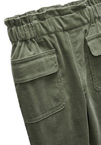 Pantalons en velours côtelé vert olive avec une taille élastique, deux poches avant et une texture côtelée marquée.