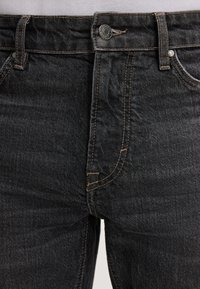 Jeans in denim scuro con vestibilità slim, dotati di chiusura con bottone metallico, cuciture a contrasto e classico design a cinque tasche.