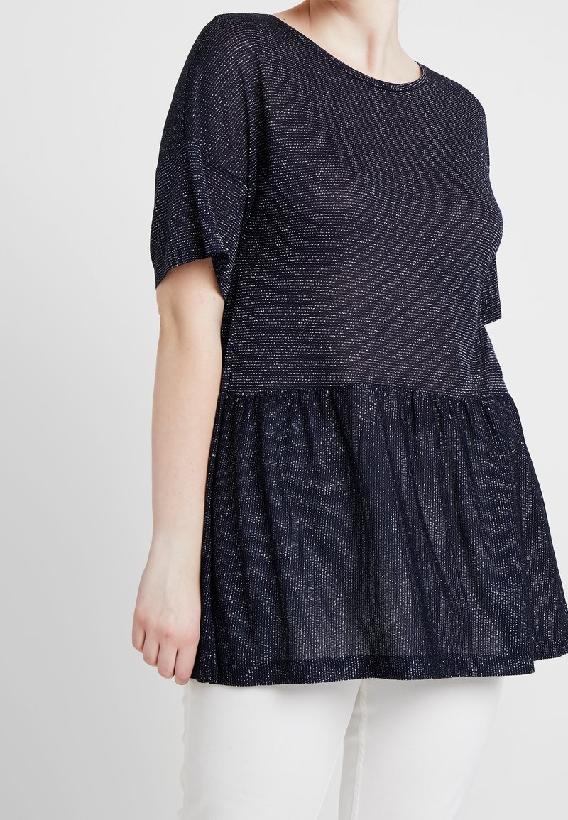 Marinblus, kortärmad topp med en texturerad yta med metalltrådar och peplumslut. Tyget är lätt och något genomskinligt.