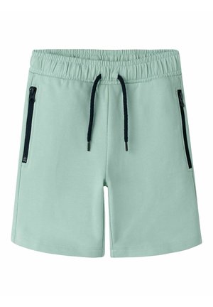 Shorts décontractés vert clair avec taille élastique, cordon noir et poches latérales zippées noires, vue de face sur fond blanc.