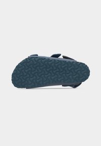 Μπλε σανδάλι φαίνεται από κάτω, με υφασμένο μοτίβο στην ελαστική σόλα και ρυθμιζόμενους ιμάντες ορατούς στο πλάι.