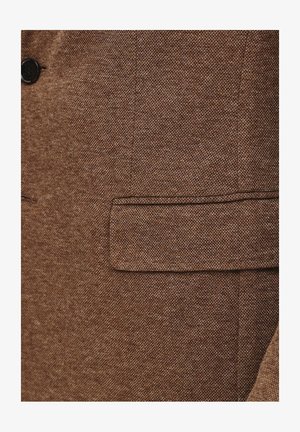 Brązowa marynarka z teksturowanej tkaniny z jednym czarnym guzikiem i kieszenią ze skrzydełkiem. Materiał ma wzór tkany z subtelną wariacją kolorystyczną.