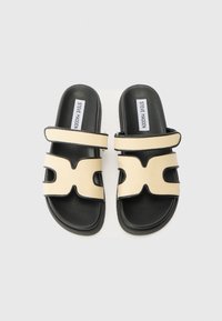 Black and beige slide sandals with two wide straps; smooth leather base, textured fabric uppers featuring cut-out designs and adjustable Velcro.