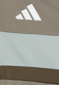 Grå och ljusblå textil med horisontella ränder; har en vit Adidas-logotyp. Materialet har en texturerad yta.
