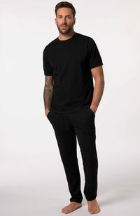 Černé bavlněné tričko a odpovídající kalhoty. Krátké rukávy, kulatý výstřih, uvolněný střih a boční kapsy. Na holých nohách je vidět tón pleti.