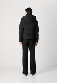 Zwarte pufferjack met een capuchon, met horizontaal gewatteerde secties en een cropped design. G gecombineerd met zwarte, wijde broek.