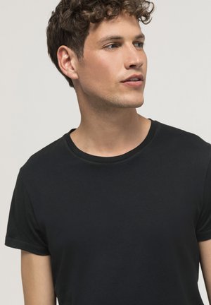 Camiseta de algodón negra con mangas cortas y cuello redondo. La tela parece suave y liviana, con detalles de costura mínimos.